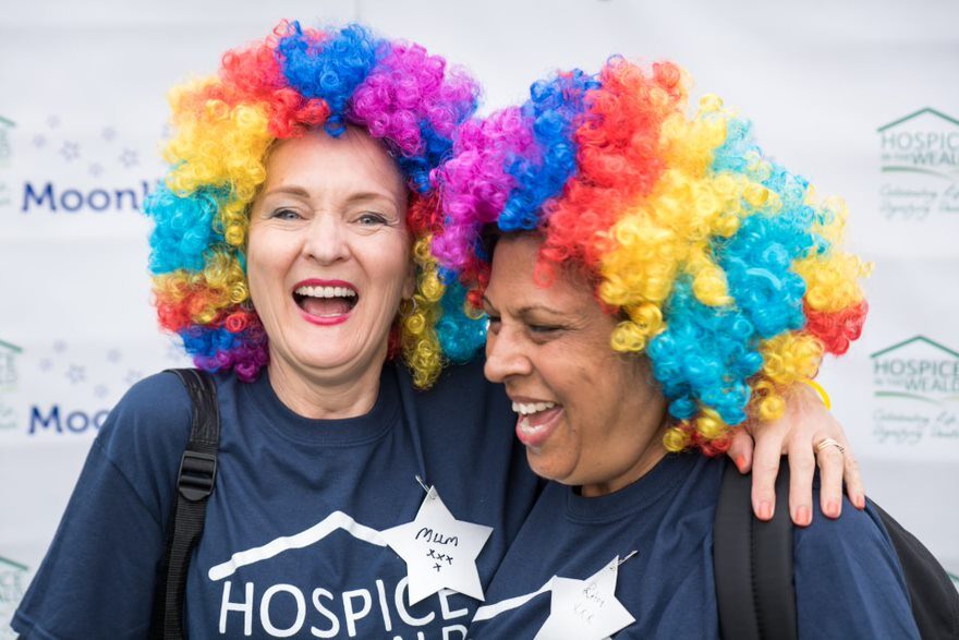 Two women at Moonlight Walk, wearing multicoloured wigs, laughing together